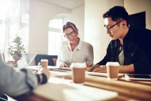 smiling-coworkers-discussing-paperwork-at-a-table-GZ3YNWD